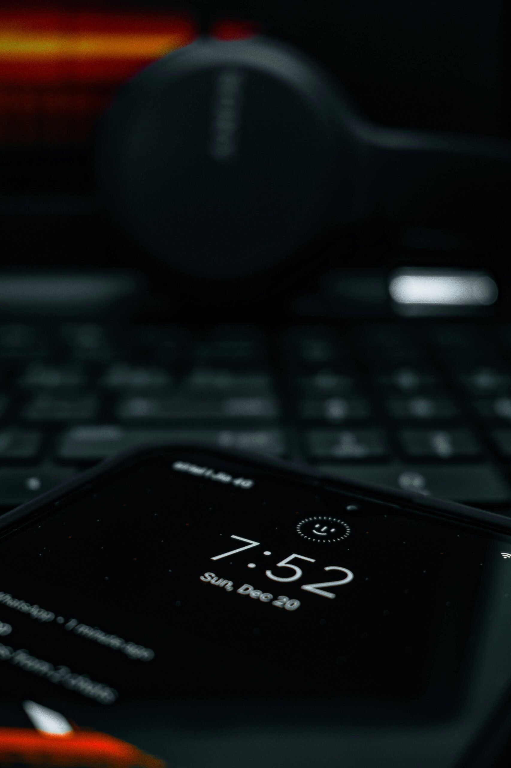 A smartphone showing time with a blurred laptop and headphones in the background, creating a tech-focused scene.